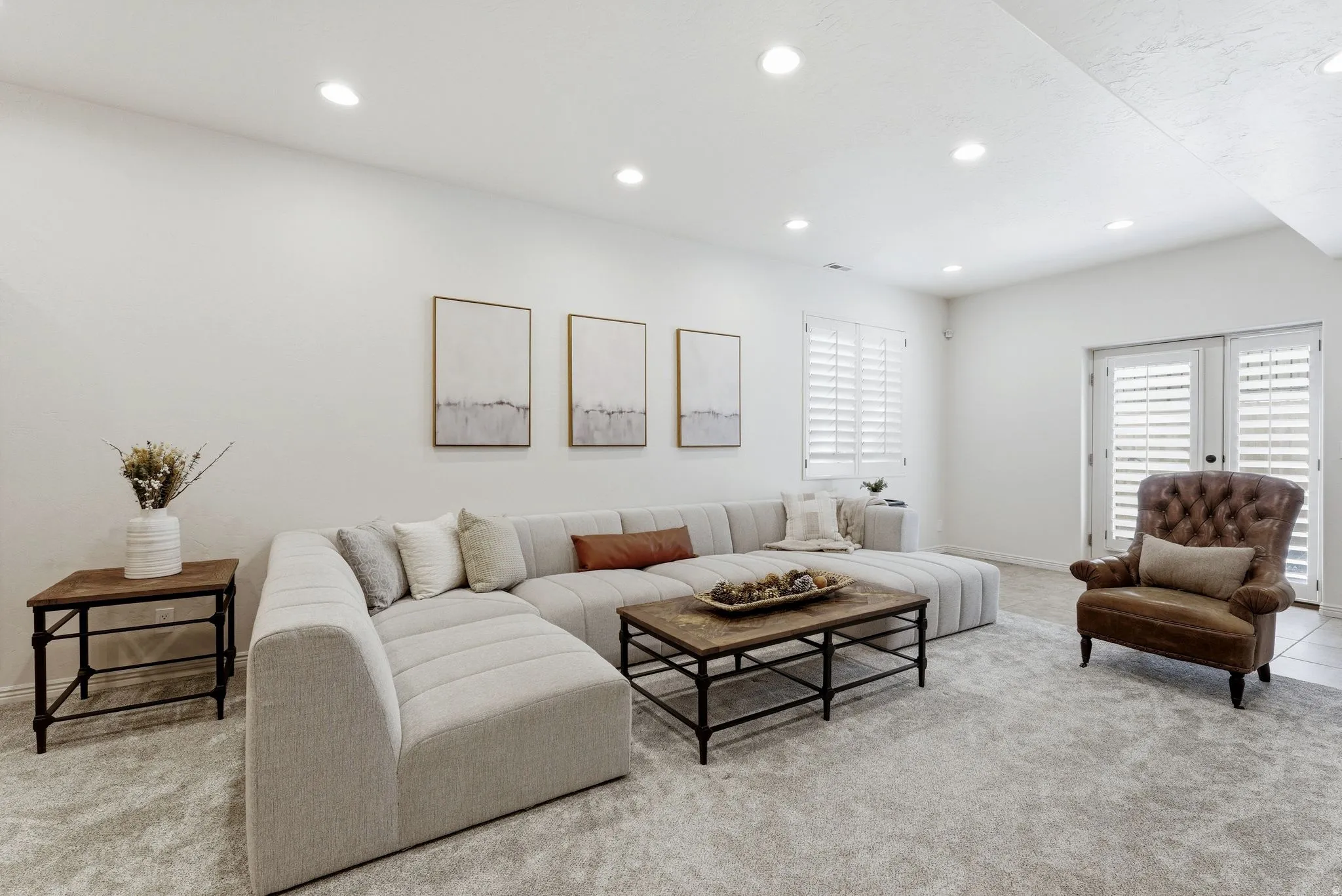 Recessed lighting illuminating a spacious room with light-toned wall finishes and plush carpeting