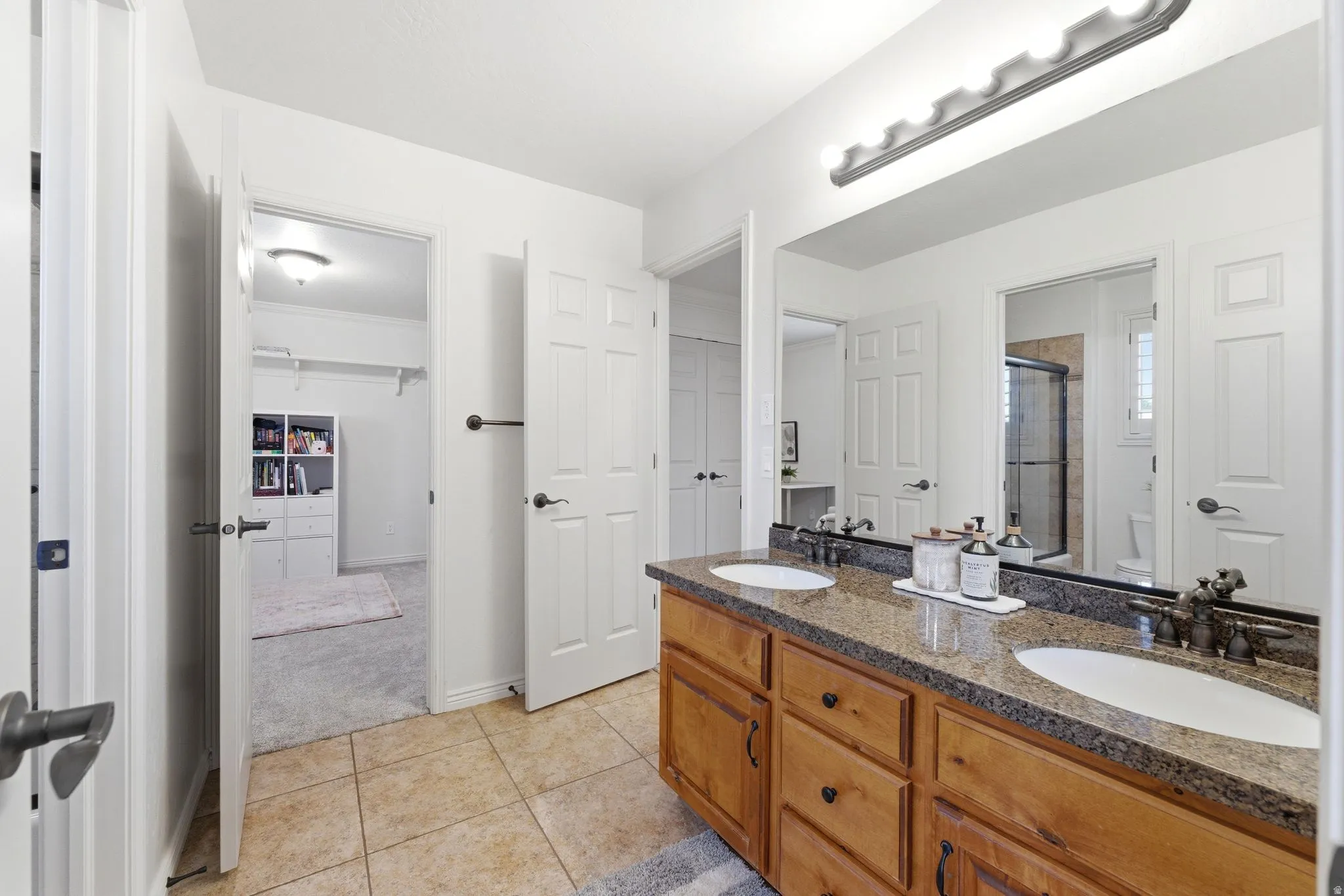 Bathroom featuring a double vanity with wood cabinetry, a granite-look countertop, and dual oval undermount sinks