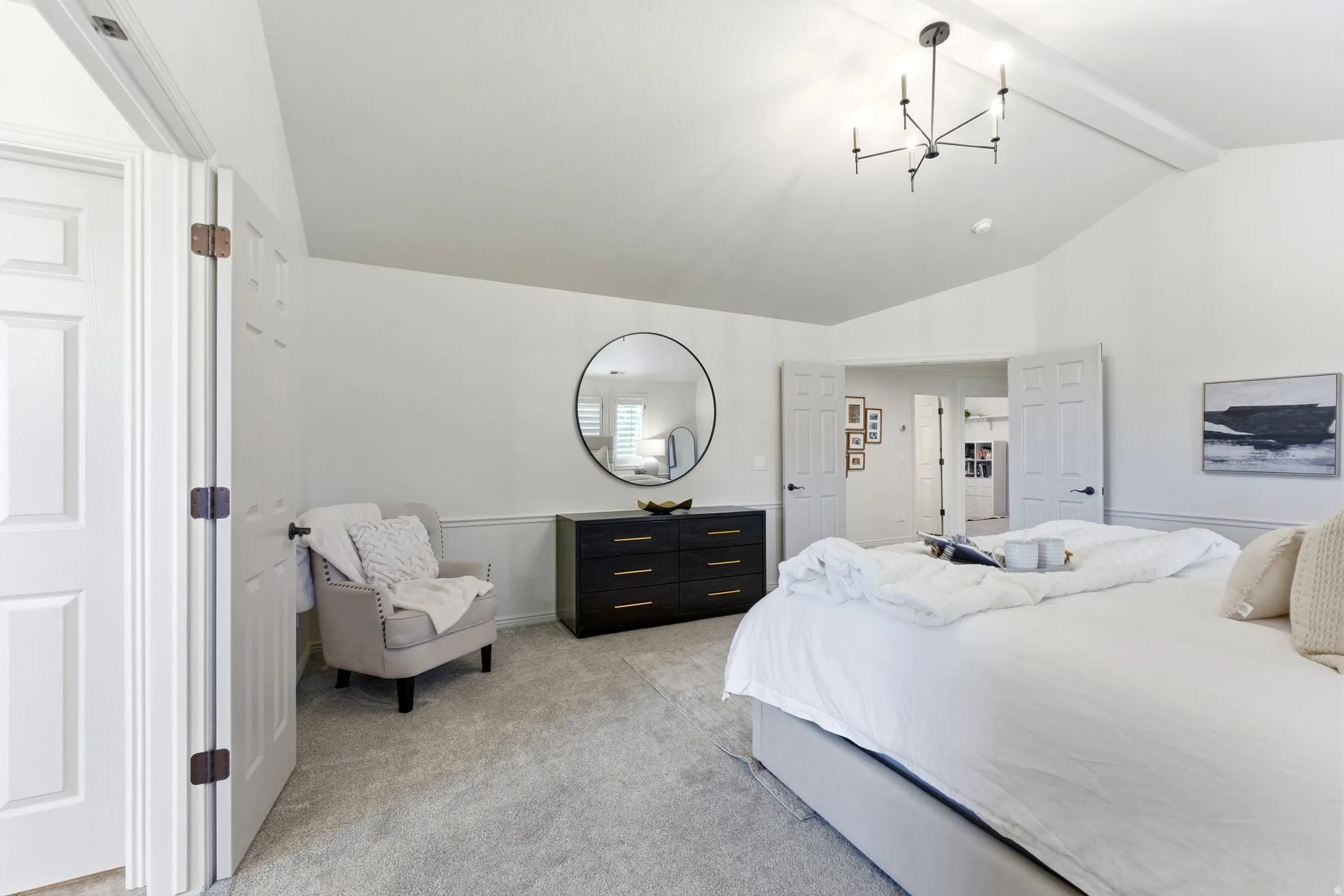 Spacious bedroom featuring vaulted ceilings, light gray carpeting, and white paneled doors