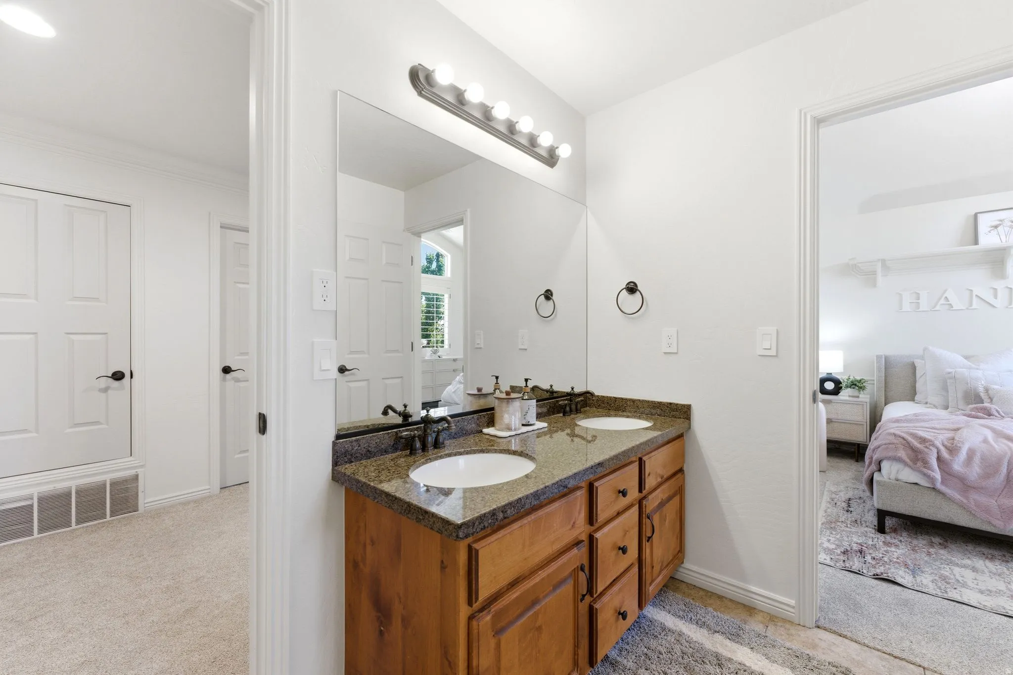 Double vanity with a speckled countertop, integrated sinks, and dark bronze-finish fixtures