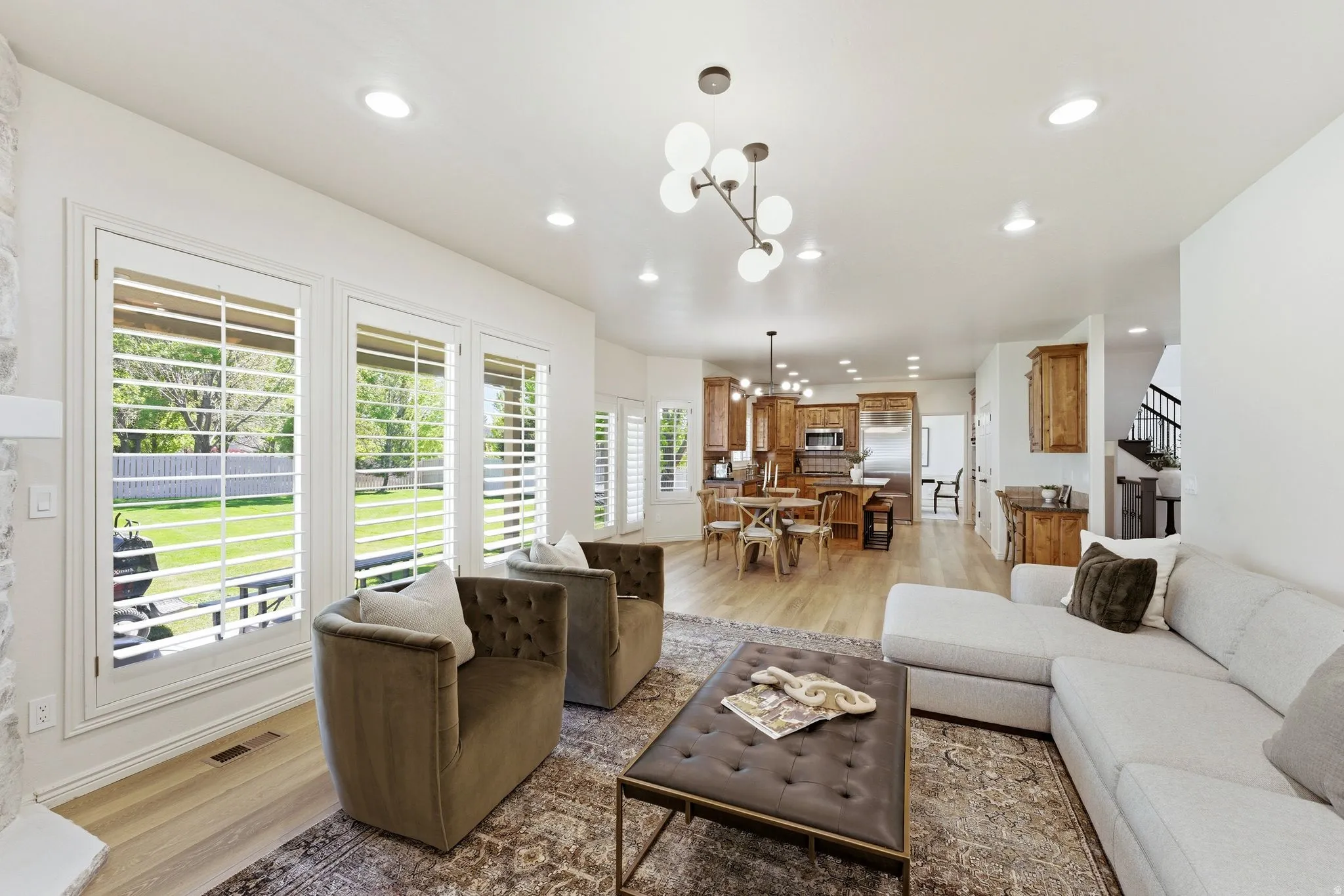 Open-concept living space featuring wood-finish flooring, recessed lighting, and a modern chandelier