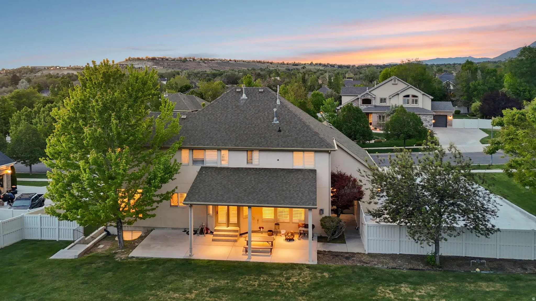 Rear exterior featuring a covered patio, extensive concrete slab, and a spacious lawn