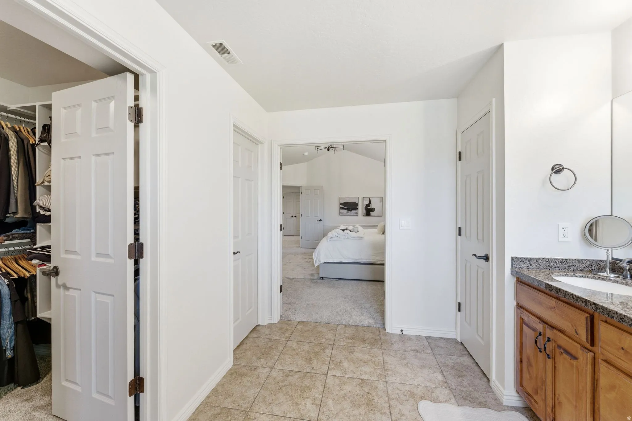 Spacious tile flooring area featuring a built-in wood vanity with a stone countertop and an under-mount sink