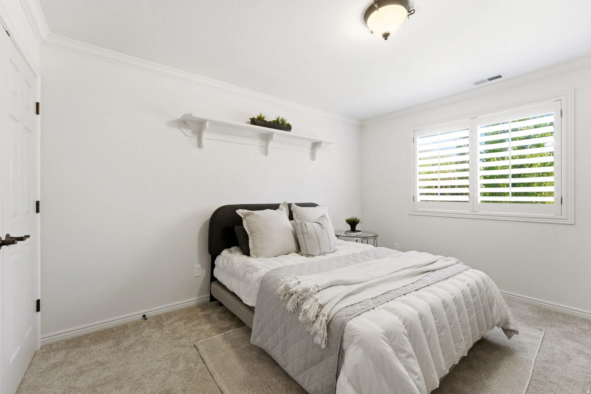 Room featuring white walls, crown molding, and light-toned carpet flooring
