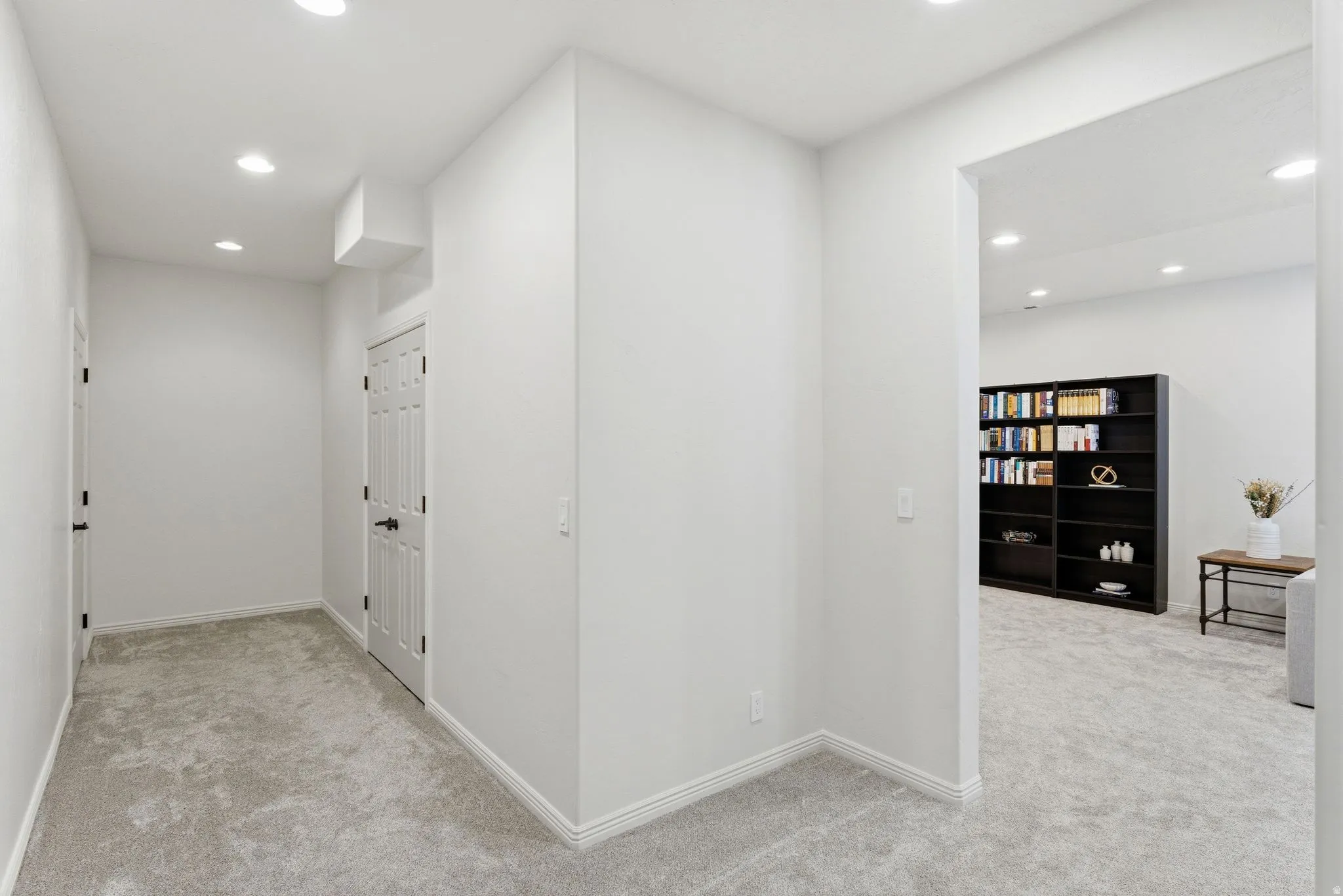 Hallway with light gray carpeting, white walls, recessed lighting, and white baseboards