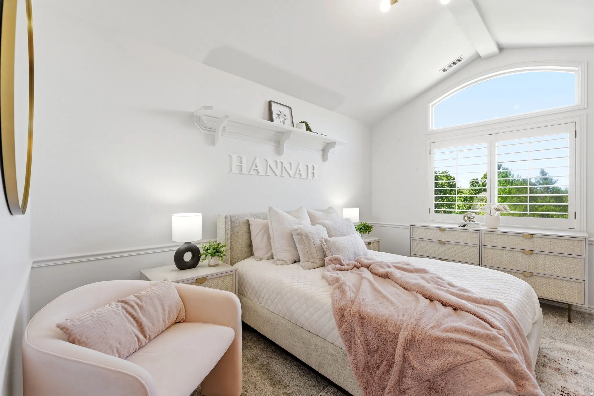 Vaulted ceiling with an arched transom window, a large rectangular window with white plantation shutters, white wall paneling, and wall-mounted shelving