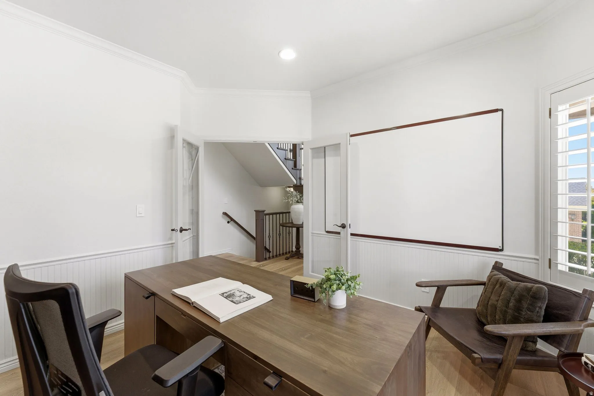 Bright room featuring white walls, beadboard wainscoting, crown molding, and wood-finish flooring