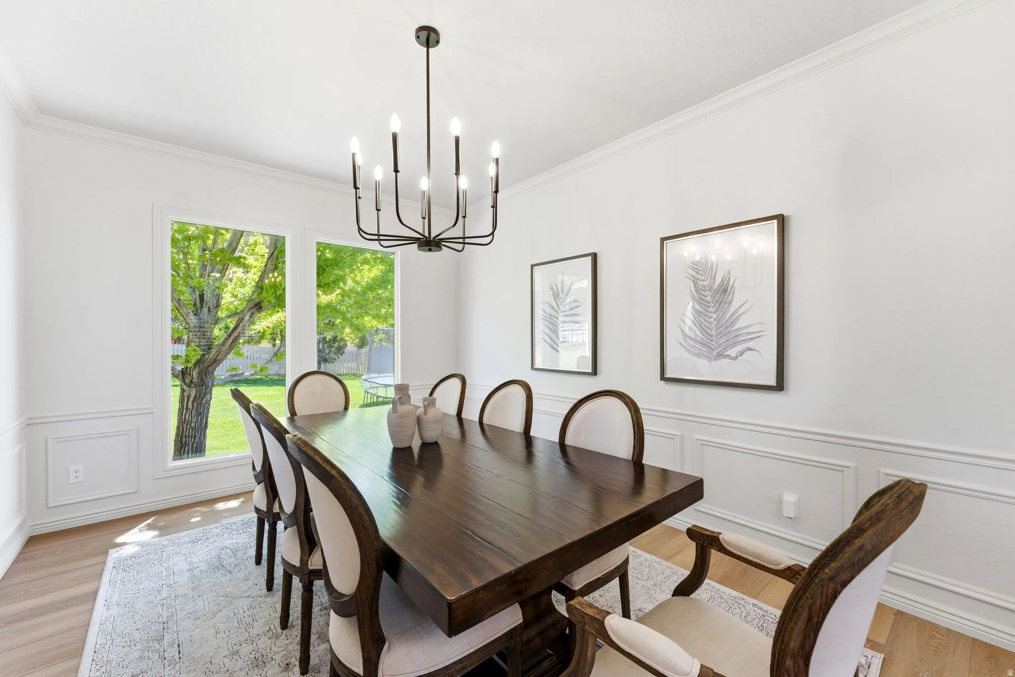 Dining area featuring a contemporary chandelier, crown molding, and wainscoting