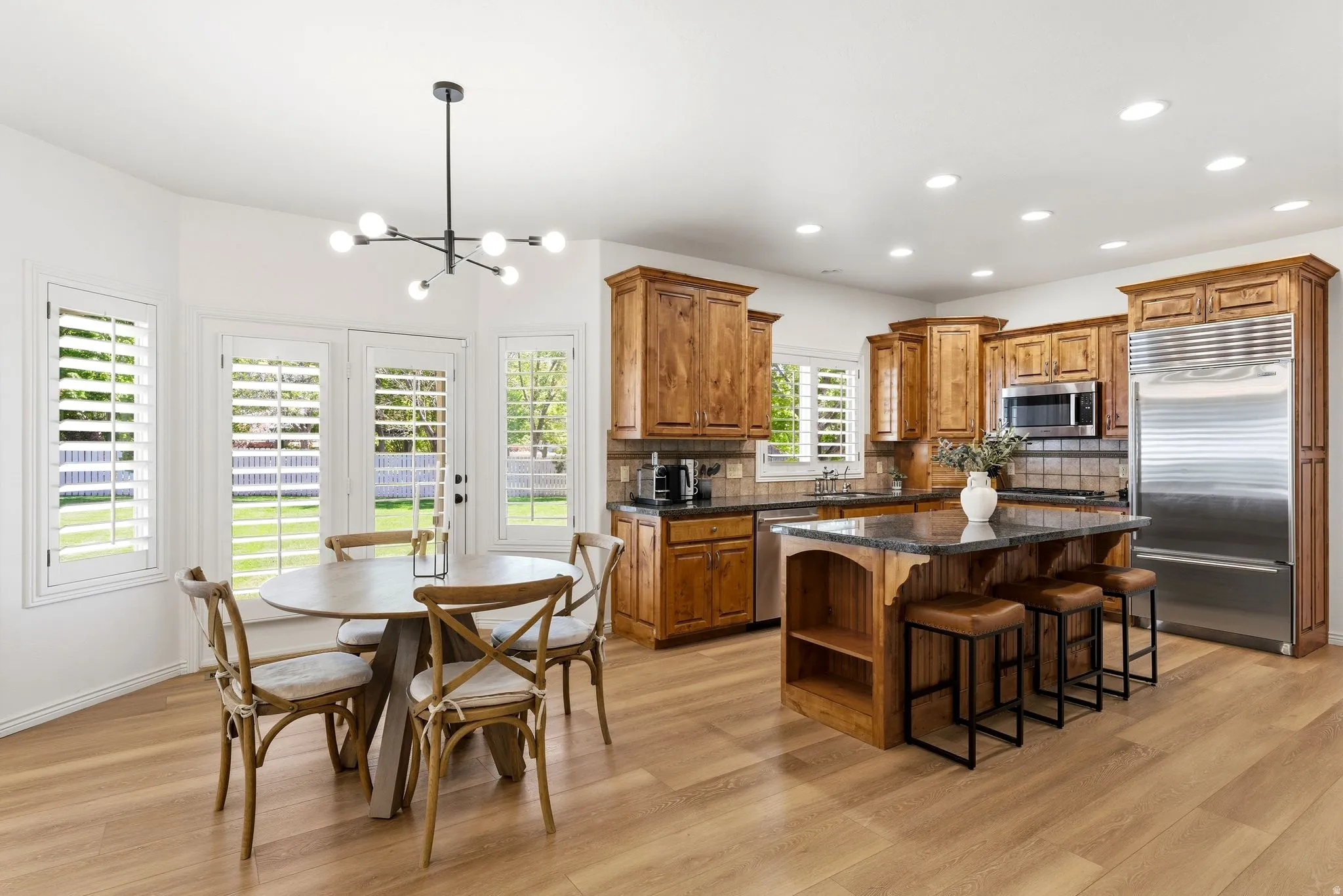 Kitchen featuring wood-finish cabinetry, a central island with countertop seating, integrated stainless steel appliances, and recessed lighting