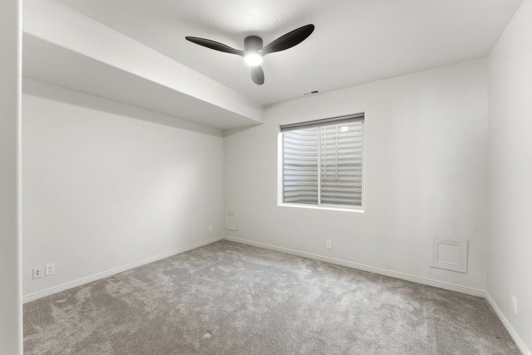 Carpeted room featuring a ceiling fan with integrated lighting, a window with horizontal blinds, and clean white walls