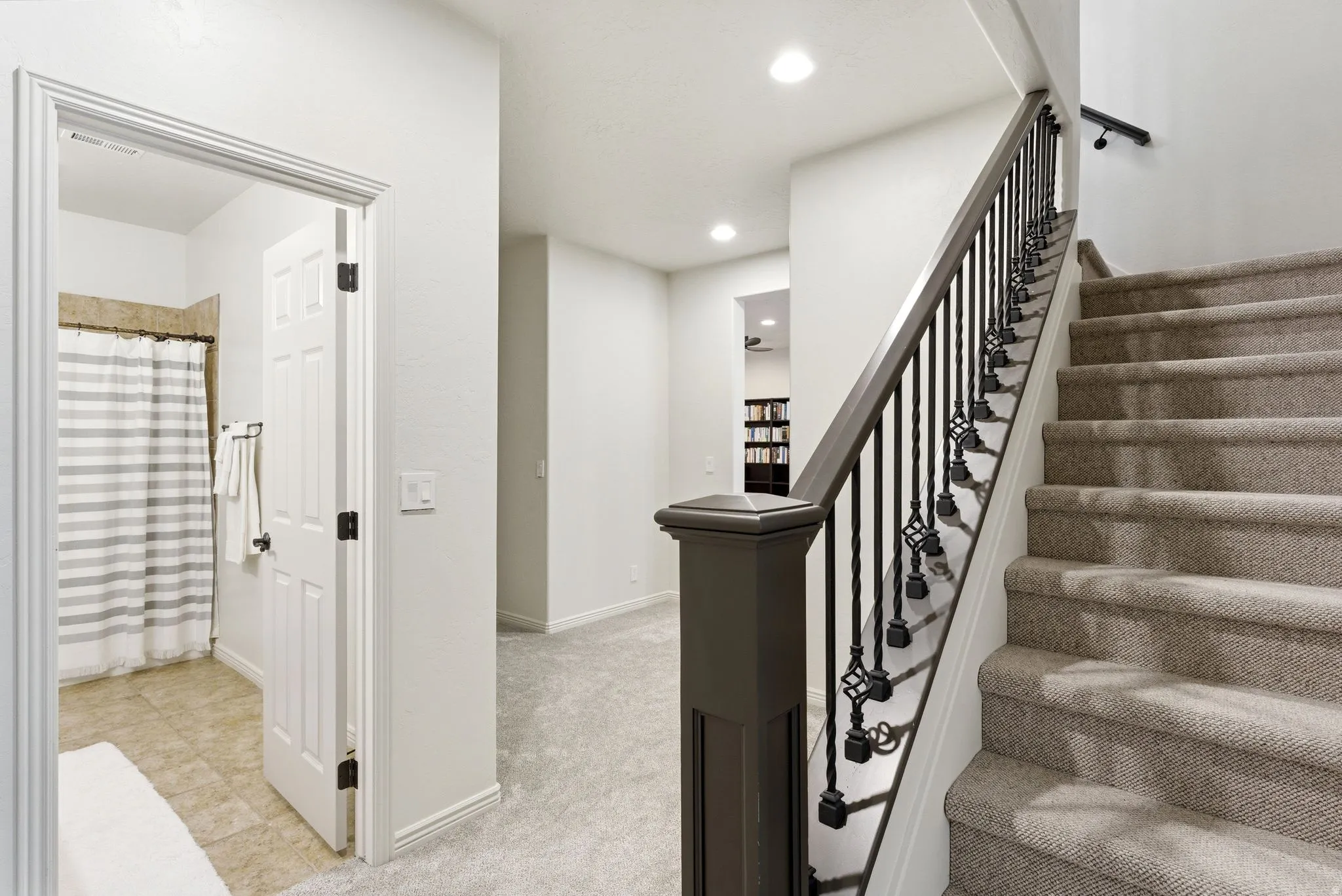 Carpeted staircase with an ornamental wrought iron and wood-finish railing