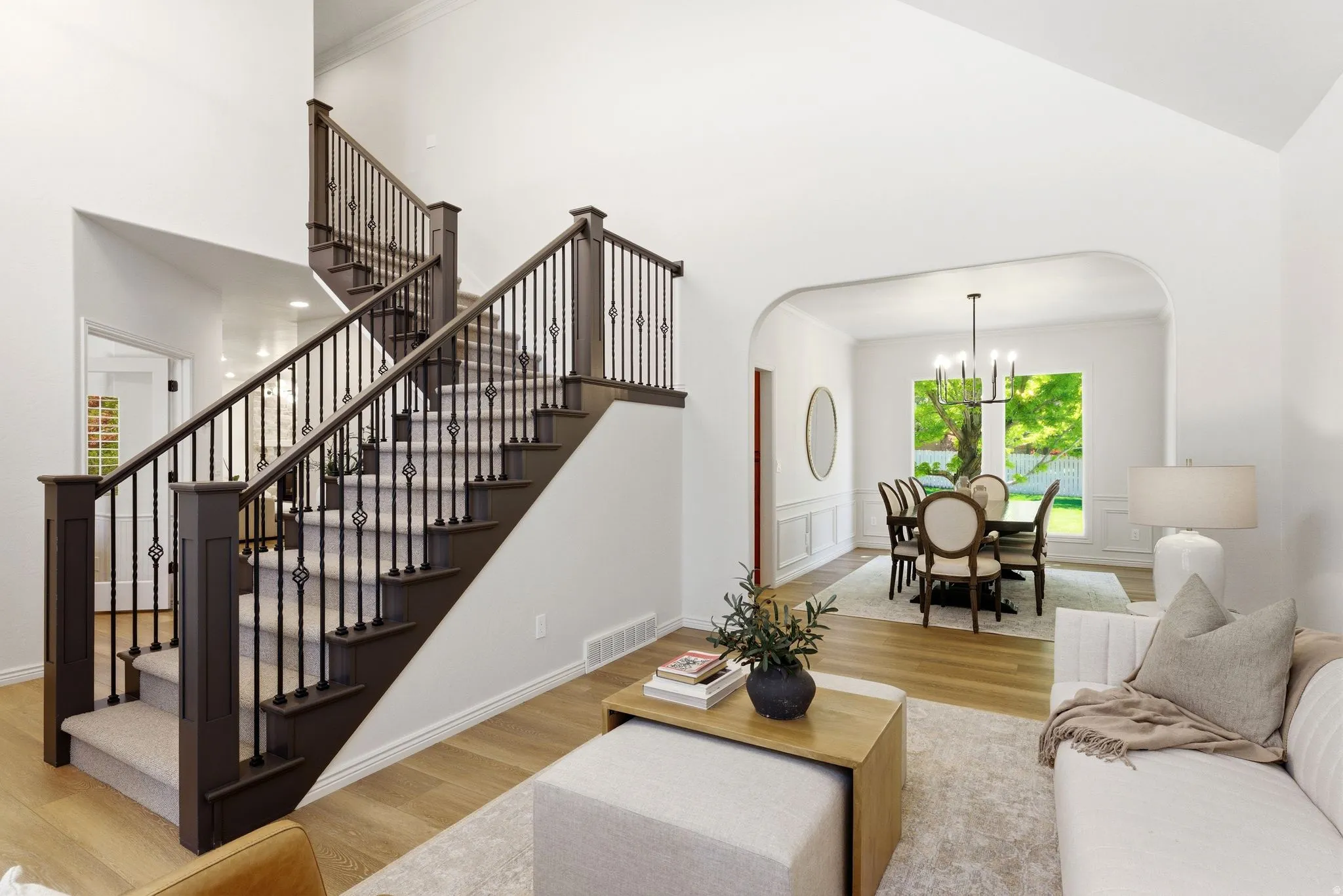 Grand staircase featuring dark wood newel posts and handrails with decorative wrought iron balusters