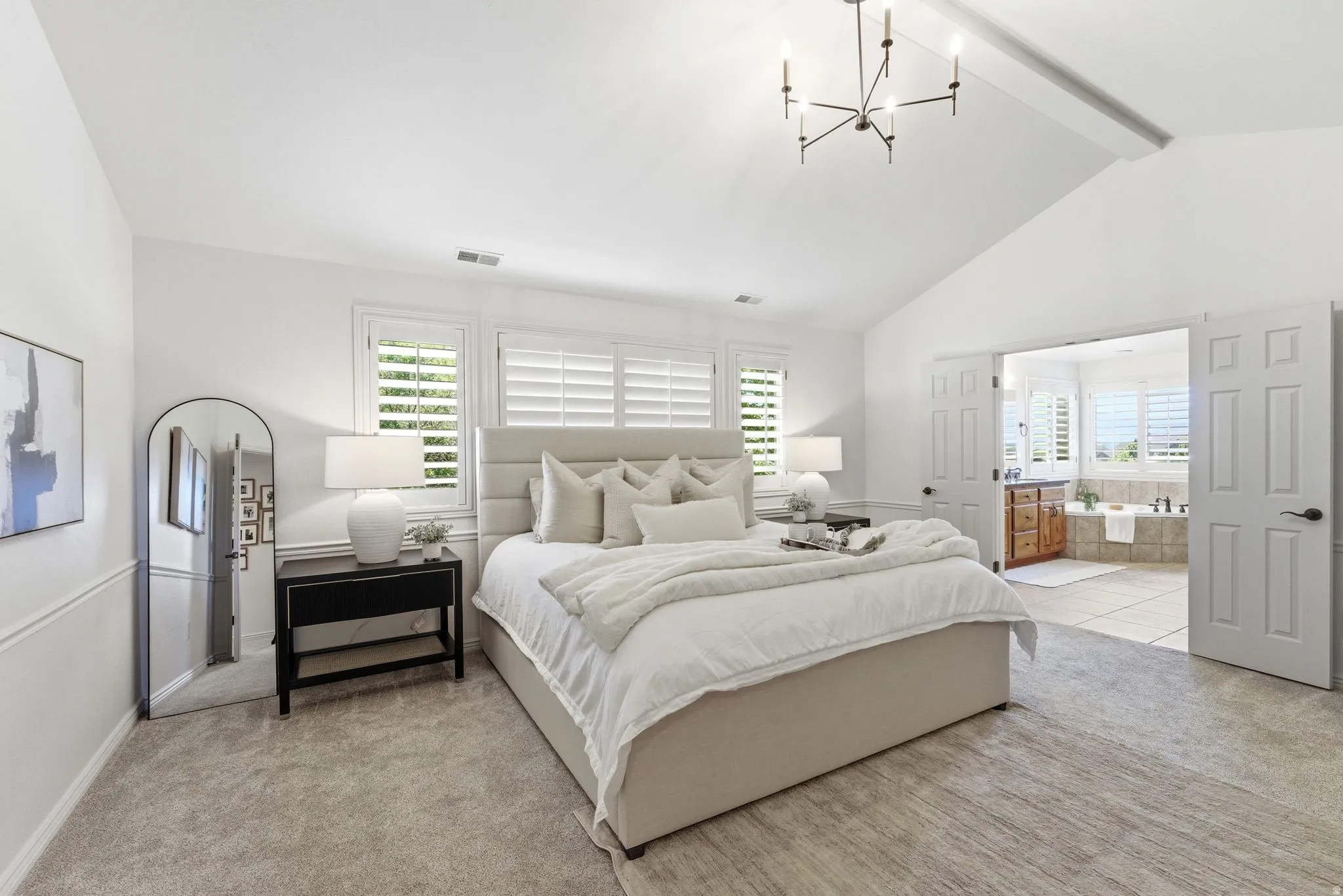 Vaulted ceilings with a contemporary chandelier and plush carpet flooring