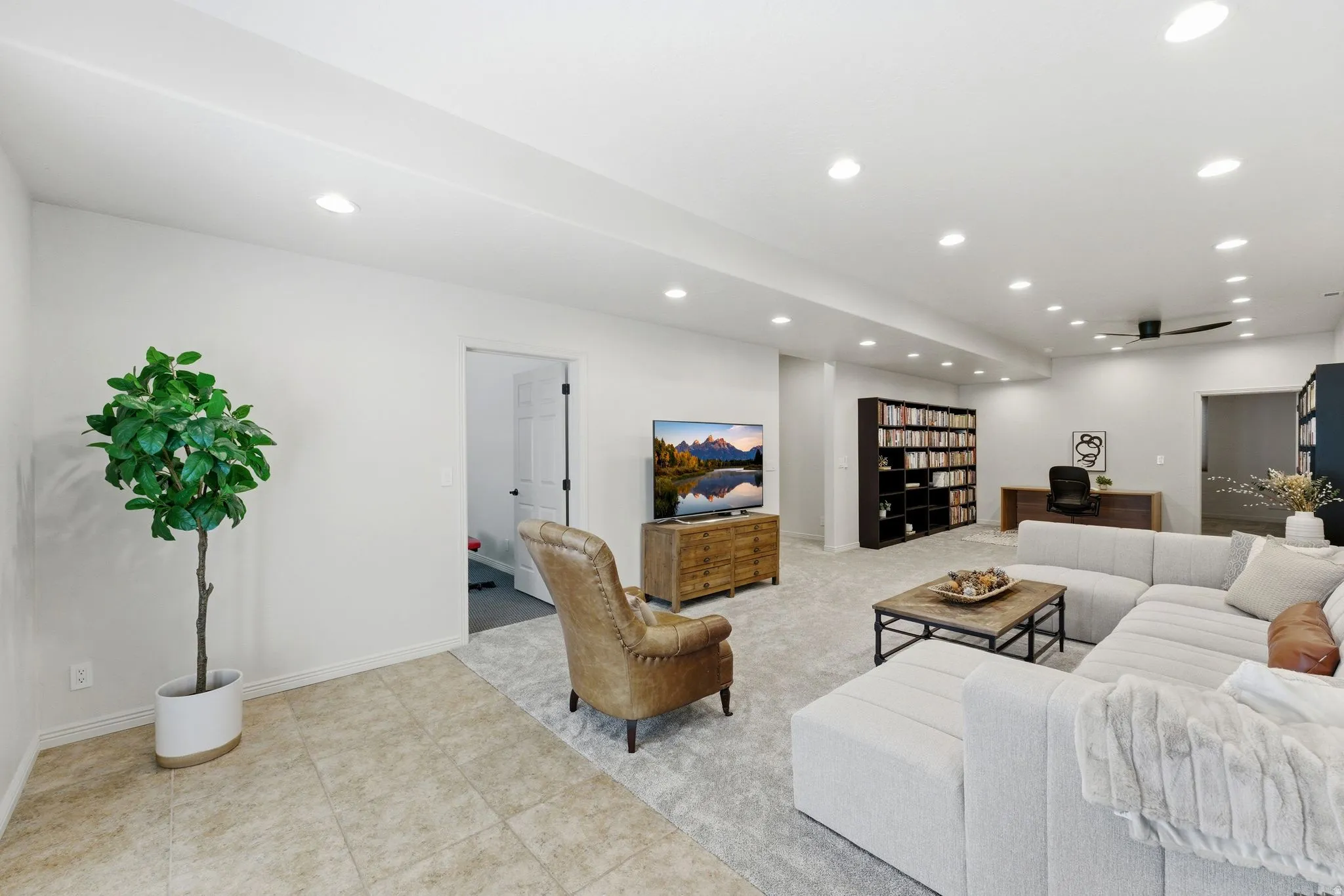 Spacious open-plan room featuring recessed lighting, light-colored walls, and a combination of tiled and carpeted flooring