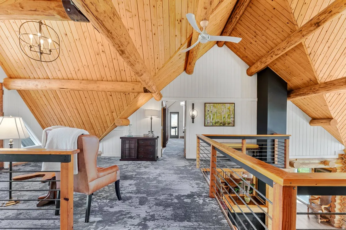Vaulted wood-plank ceilings featuring exposed timber beams, a ceiling fan, and a modern orb chandelier