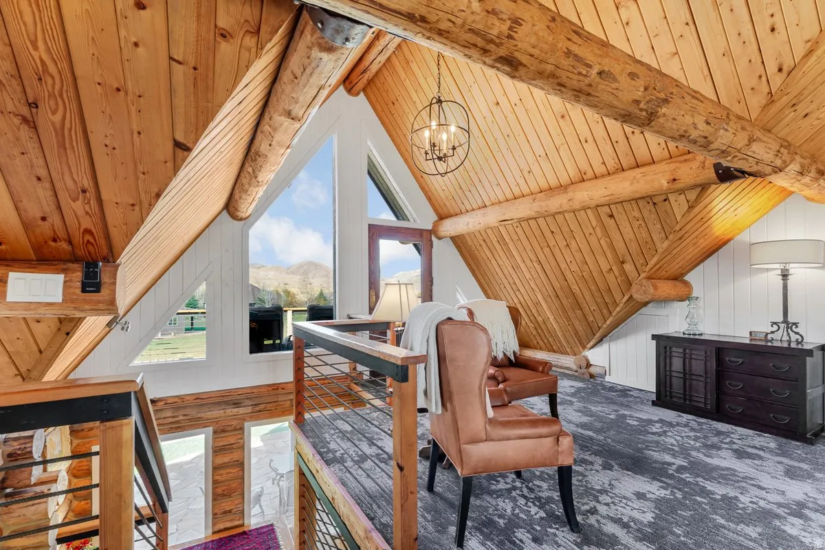 Vaulted wood-paneled ceilings with exposed log beams, large triangular windows, cable railing, and wood-finish flooring