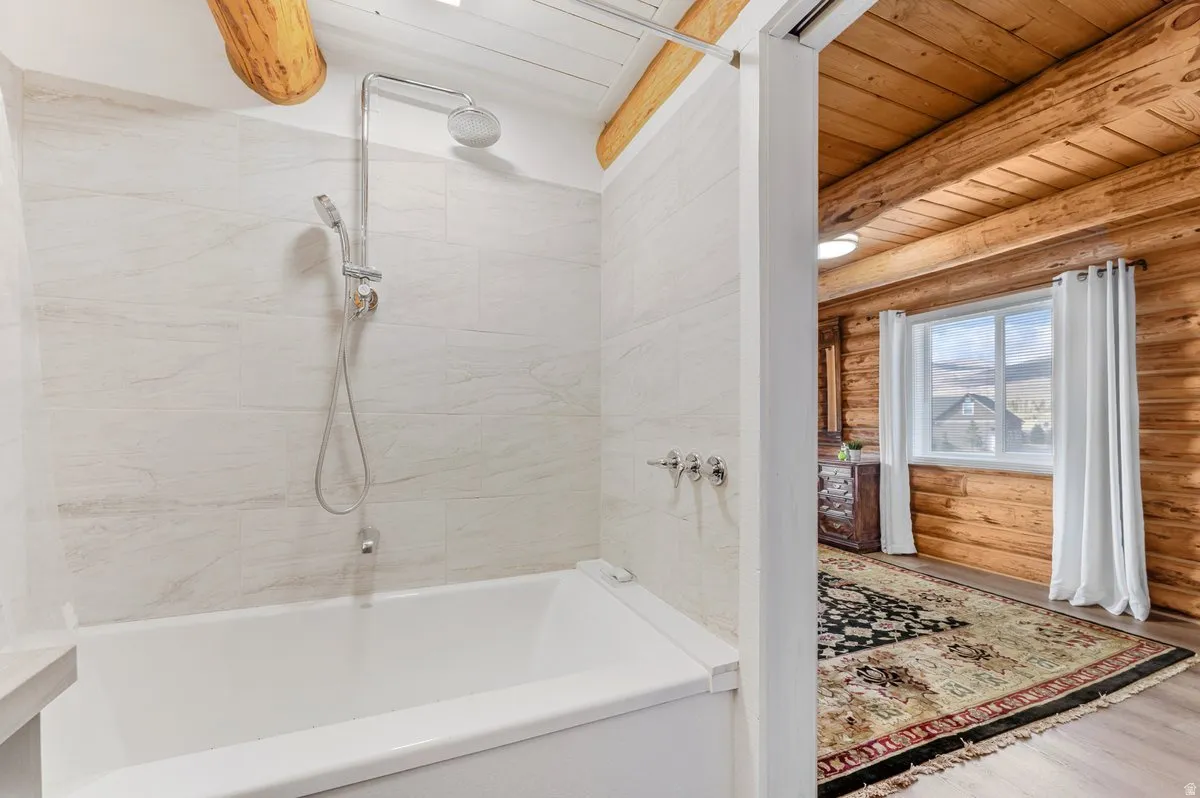 Bathtub with a handheld showerhead and light-toned tile surround