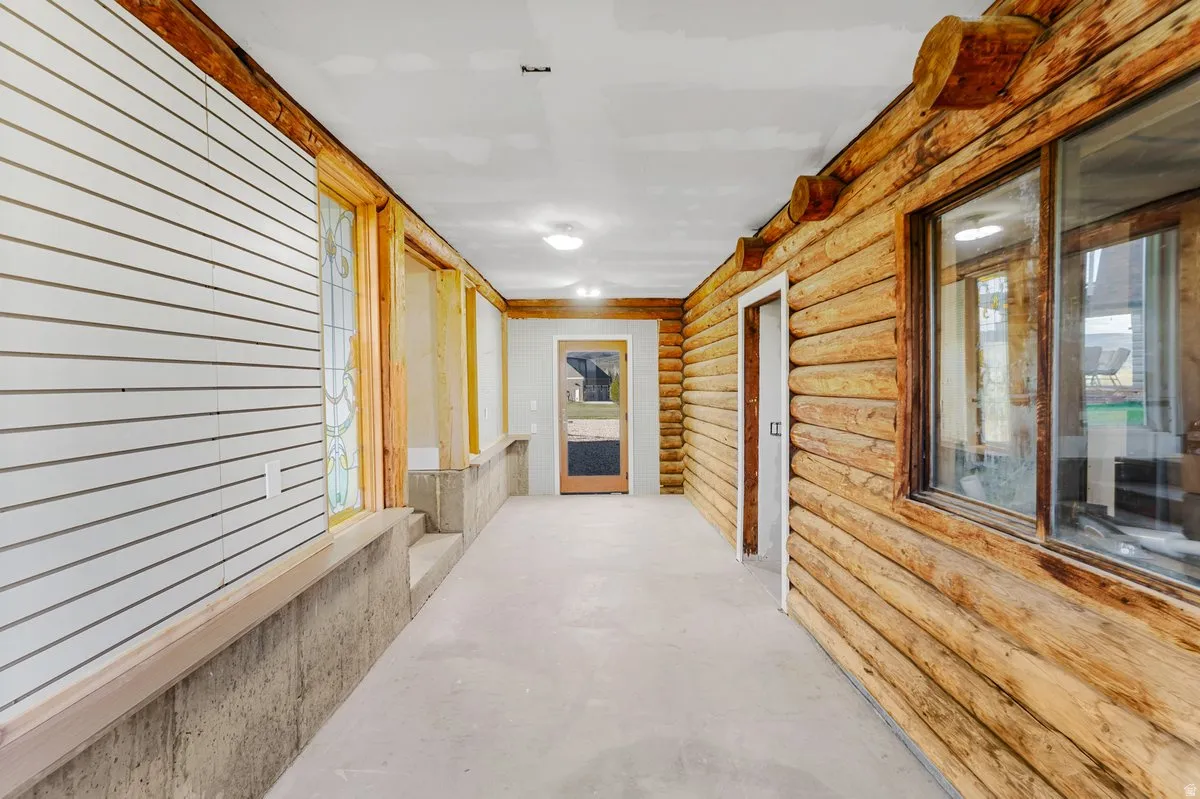 Rustic interior hallway featuring log-style walls and an exposed concrete floor