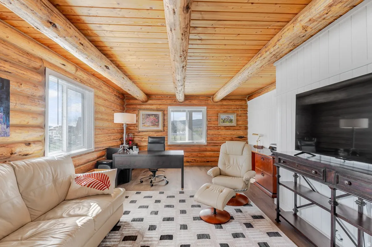 Interior space featuring log walls, exposed wood beams, wood plank ceiling, and light-toned flooring