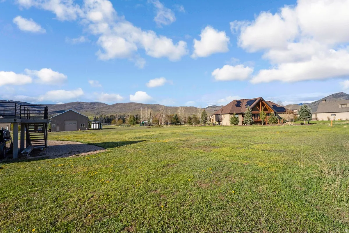 Expansive green space featuring a distant residence with a prominent A-frame architectural element, an attached deck, and solar panels