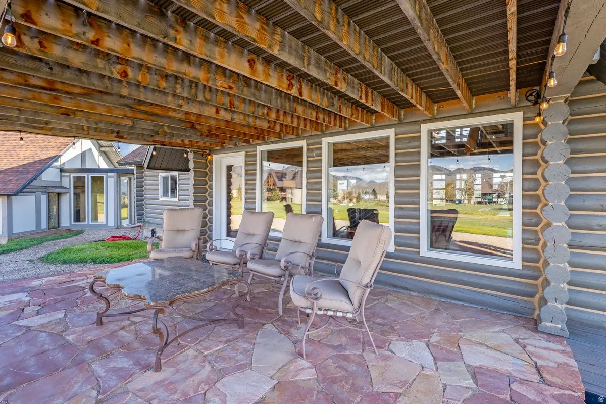 Expansive outdoor patio featuring irregular flagstone paving under a wood-beamed ceiling