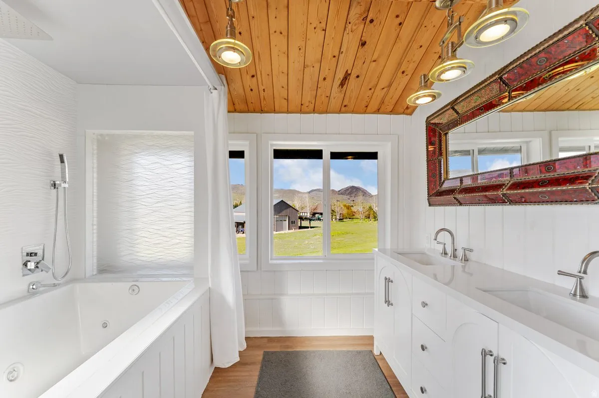 Bathroom featuring a wood-finish plank ceiling, a dual vanity with undermount sinks and modern fixtures, and a jetted soaking tub
