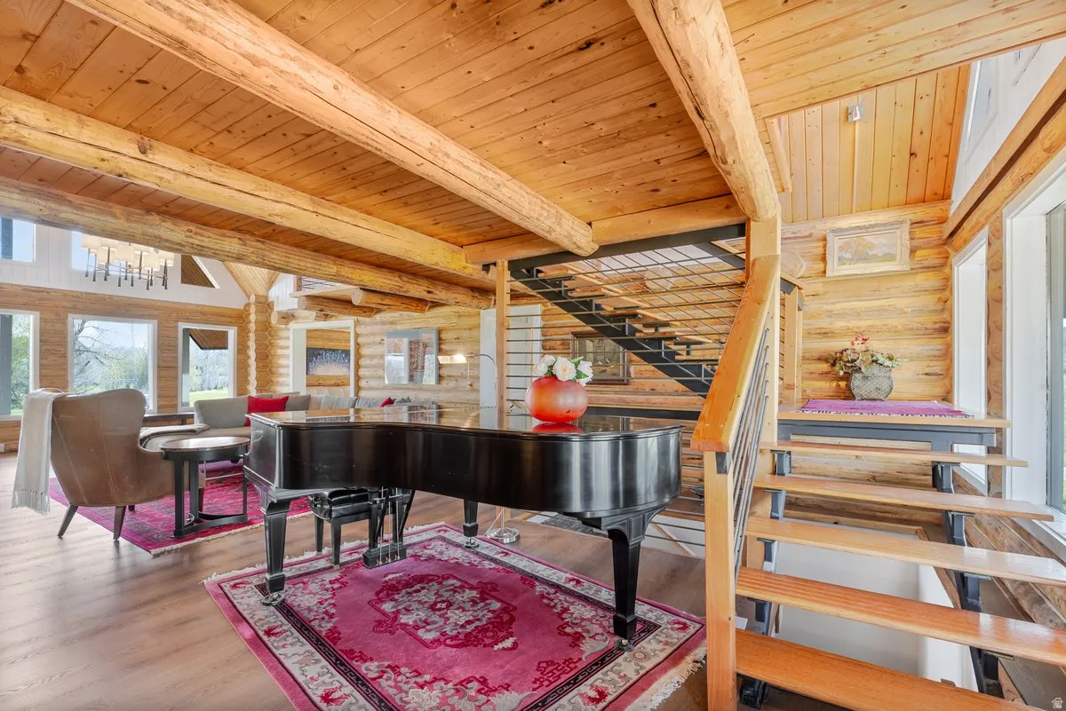Expansive open-concept interior featuring prominent wood-finish flooring, exposed wooden beams, and log wall construction