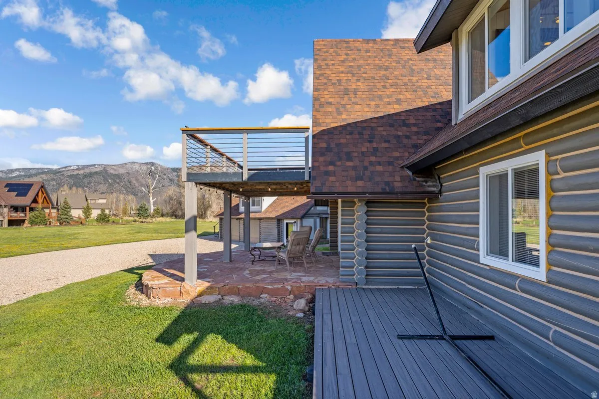 Exterior featuring gray log siding, a brown shingle roof, and white window frames