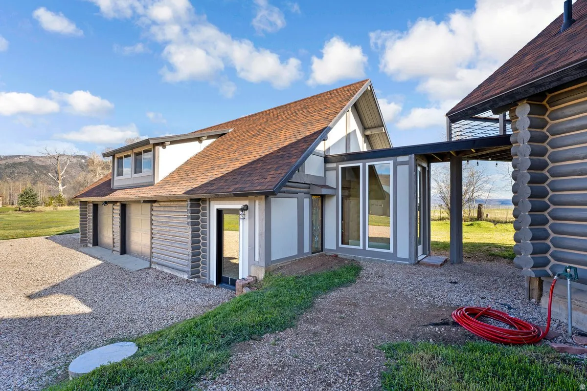 Exterior featuring a multi-gable roofline, log-style siding accents, and a gravel driveway