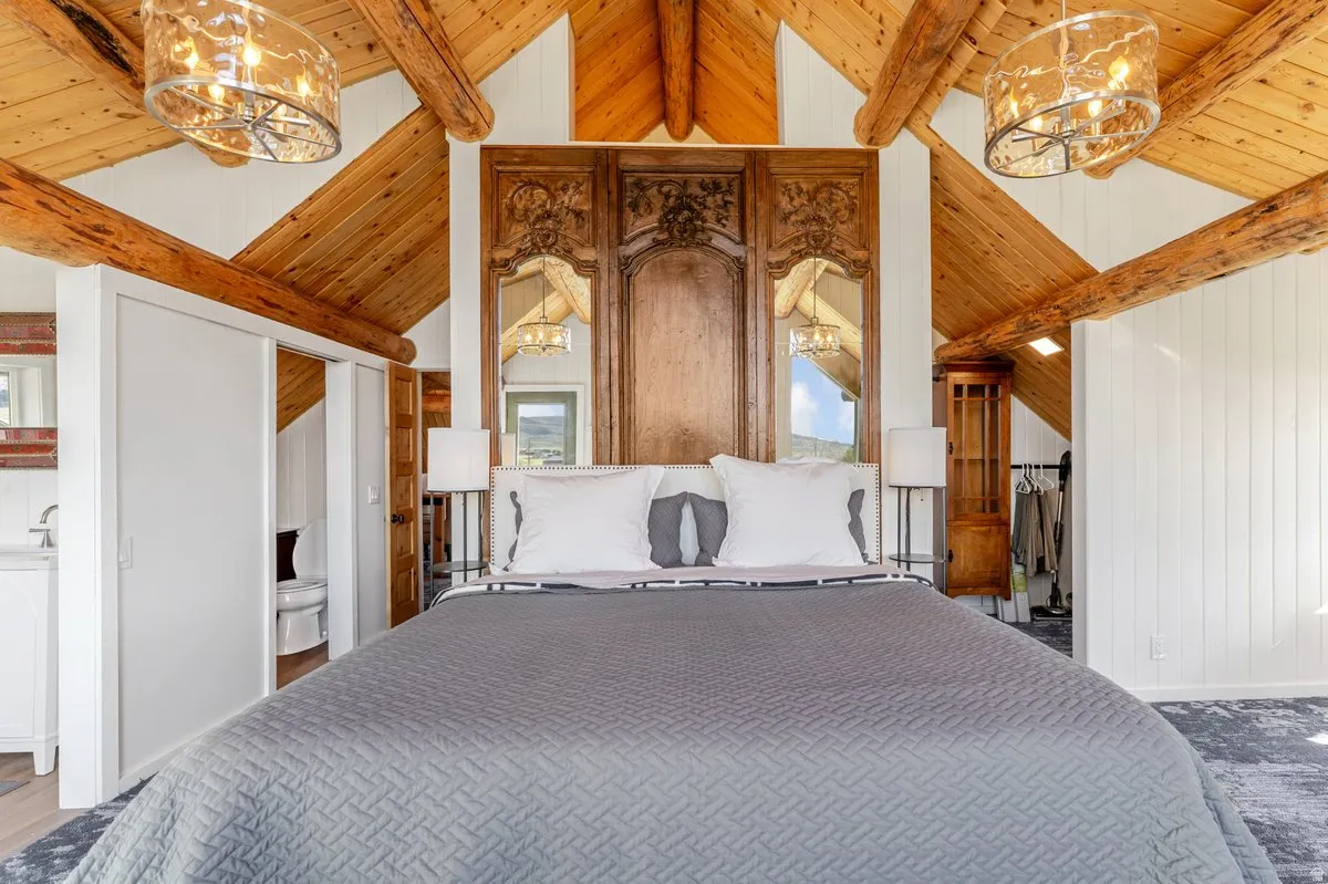 Vaulted wood-plank ceilings with exposed timber beams and two amber-toned chandeliers