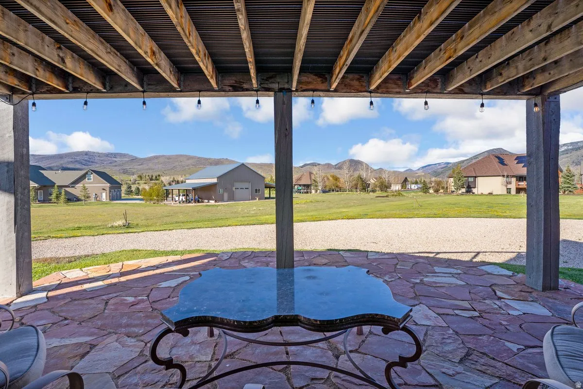 Covered outdoor patio featuring stone flooring, exposed beam ceiling, and string lighting