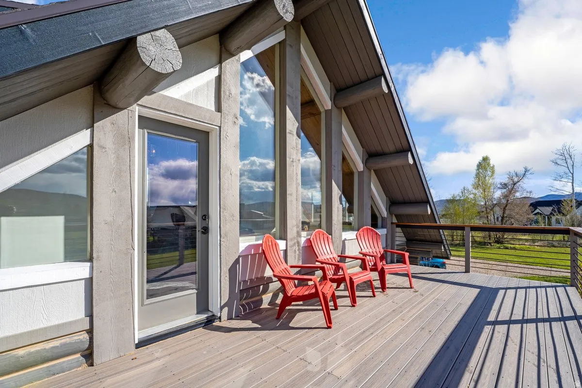 Expansive exterior deck featuring a cable railing system, a glass-paneled entry door, and large vertical windows integrated into the architectural design
