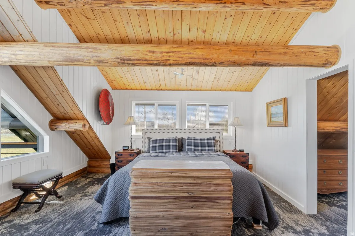 Exposed log beams and wood-planked vaulted ceiling featuring a skylight window