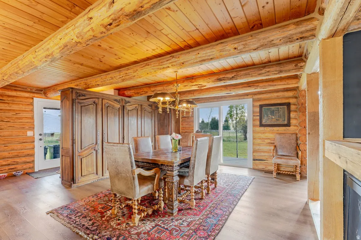 Dining area featuring wood-finish flooring, log walls, and a wood-paneled ceiling with exposed log beams