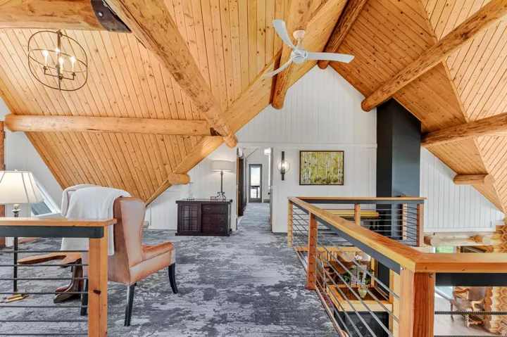 Vaulted wood-plank ceilings featuring exposed timber beams, a ceiling fan, and a modern orb chandelier