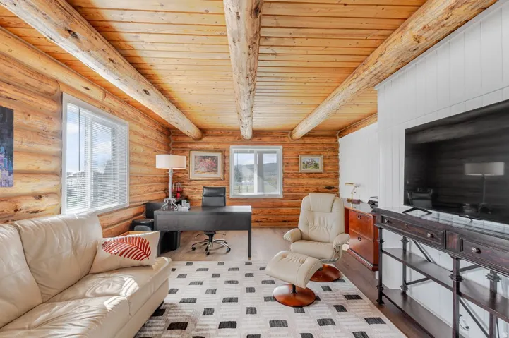 Interior space featuring log walls, exposed wood beams, wood plank ceiling, and light-toned flooring