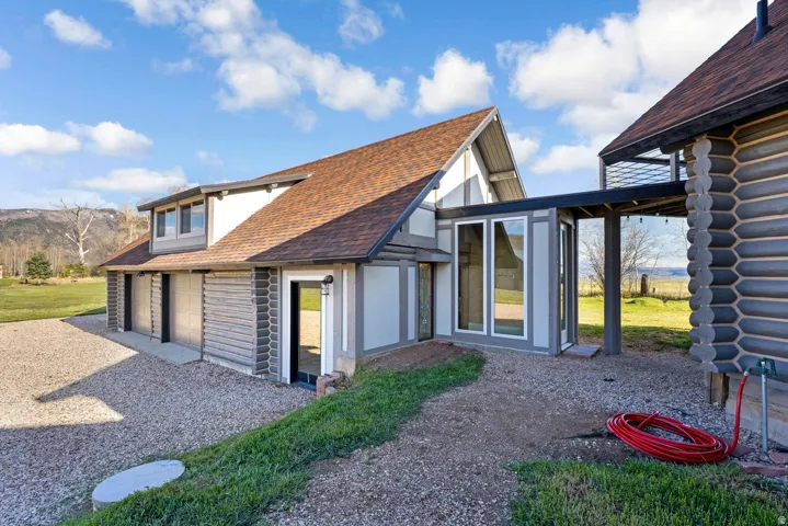 Exterior featuring a multi-gable roofline, log-style siding accents, and a gravel driveway