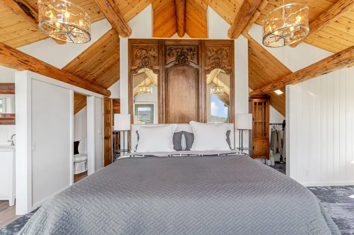 Vaulted wood-plank ceilings with exposed timber beams and two amber-toned chandeliers
