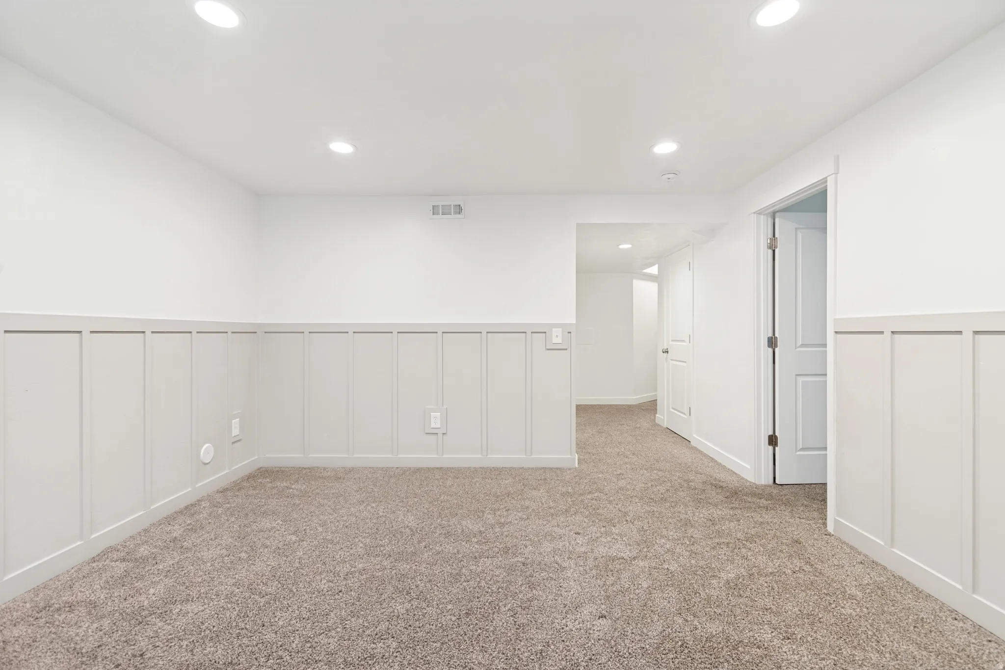 Carpeted room with white board and batten wainscoting
