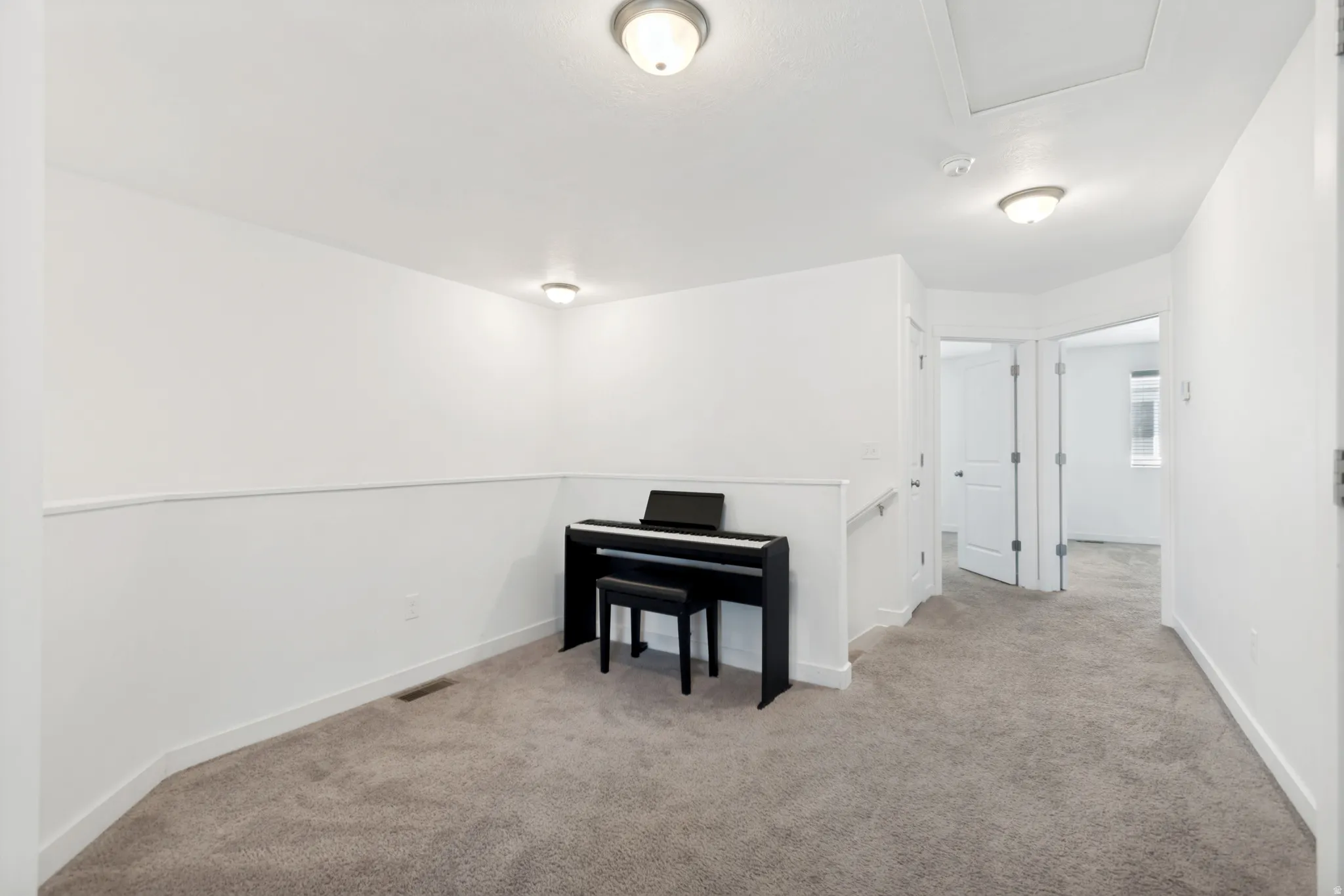 Carpeted hallway featuring white walls, baseboards, and ceiling-mounted light fixtures