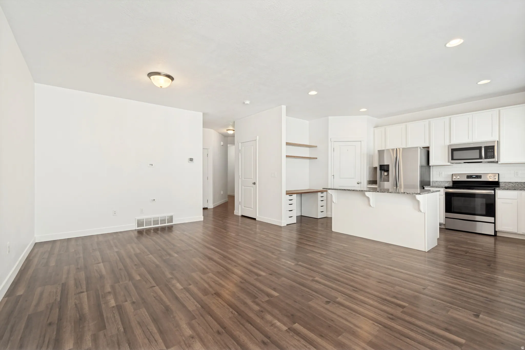 Expansive room featuring wood-finish flooring, white walls, and recessed lighting
