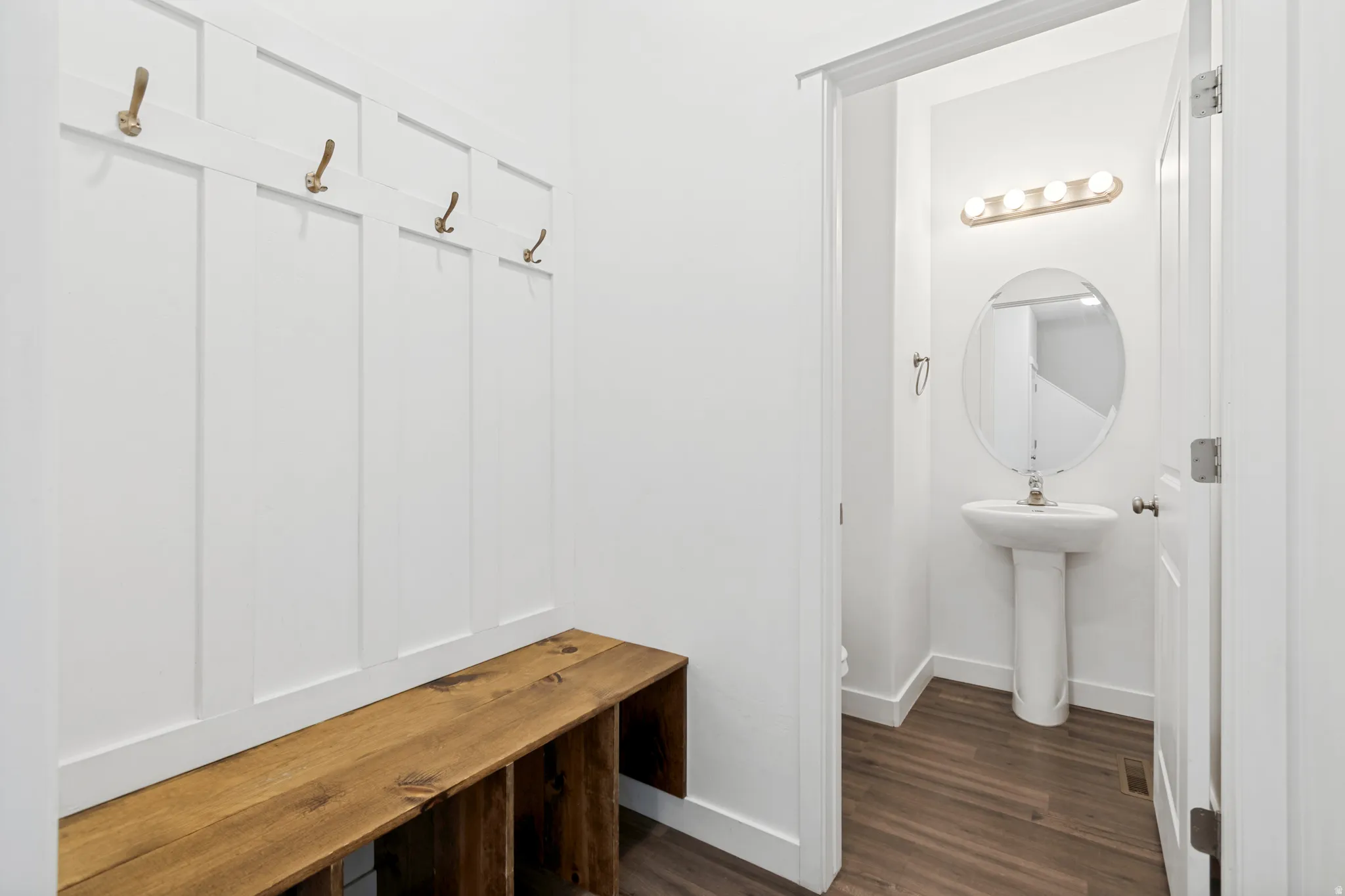 Entryway featuring white board and batten paneling with integrated hooks and a built-in wood bench