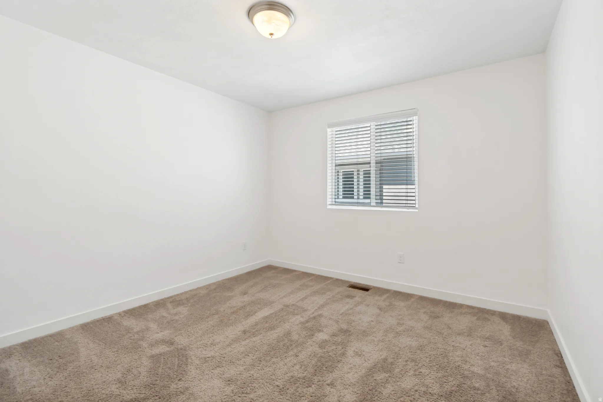 Room featuring plush neutral-toned carpeting and crisp white baseboards