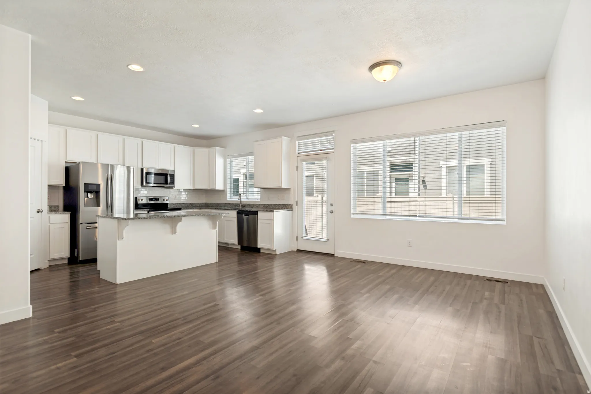 Open-concept living space featuring wood-finish flooring and multiple windows