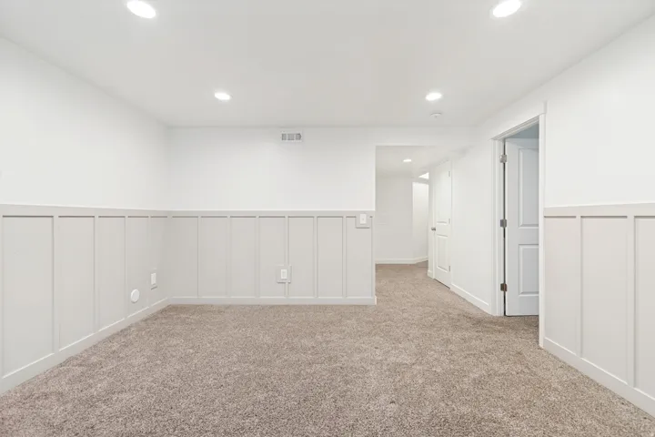 Carpeted room with white board and batten wainscoting