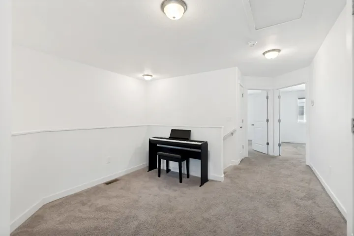 Carpeted hallway featuring white walls, baseboards, and ceiling-mounted light fixtures