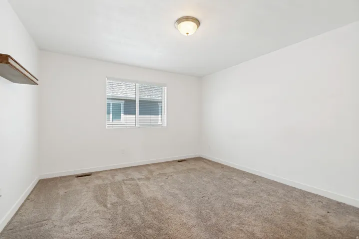 Room featuring neutral carpeting, white walls, and a window with horizontal blinds