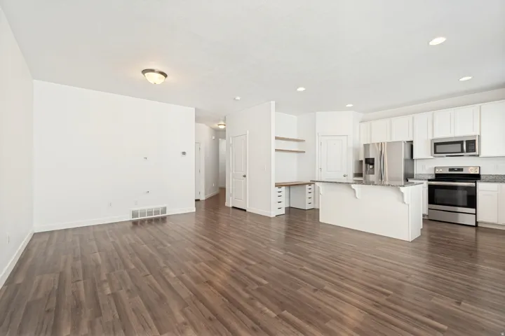 Expansive room featuring wood-finish flooring, white walls, and recessed lighting