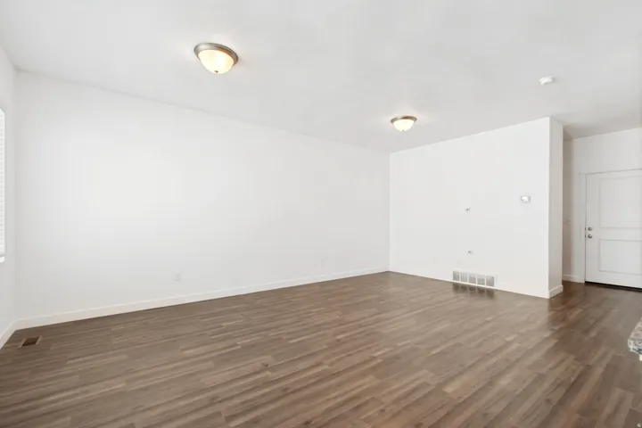 Spacious interior featuring wood-finish flooring, white walls, and flush-mount ceiling lights