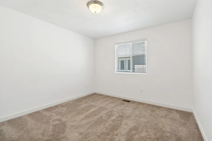 Room featuring plush neutral-toned carpeting and crisp white baseboards